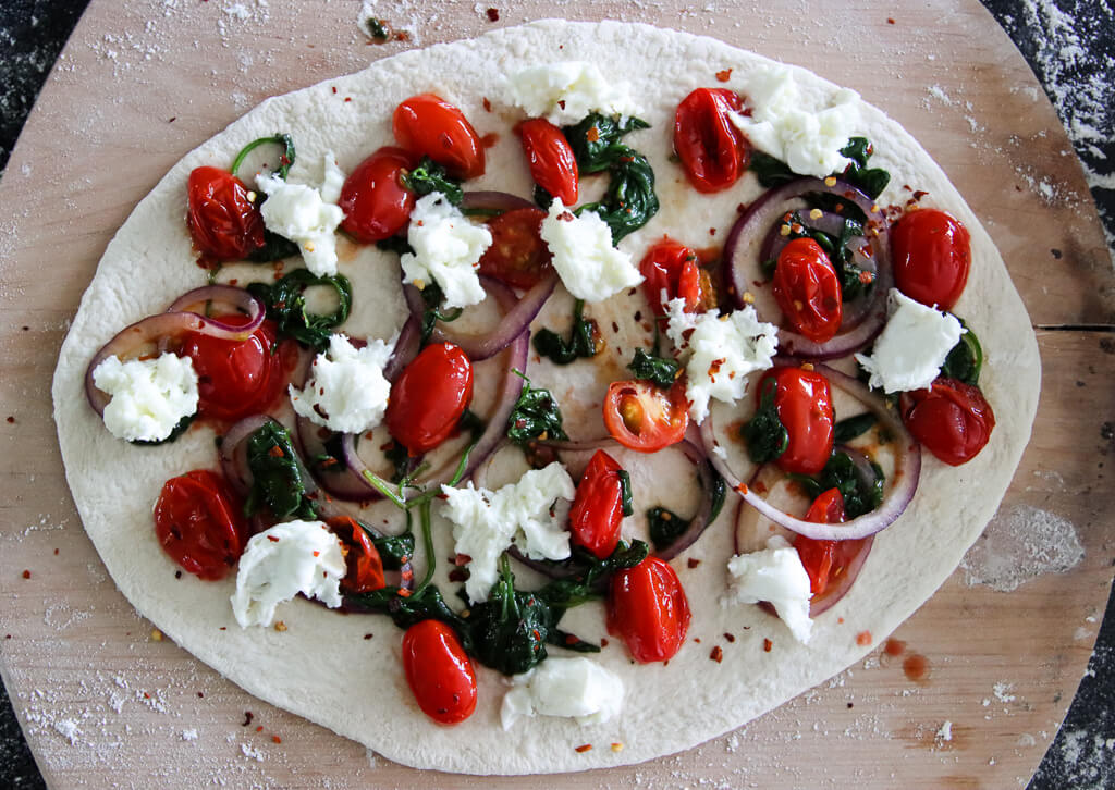 Pizza med tomat, spinat, løk og mozzarella