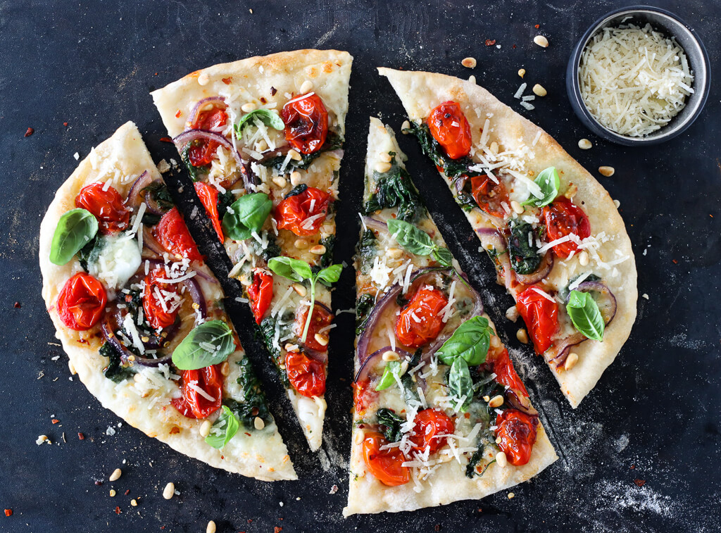 Pizza med tomat, spinat, løk og mozzarella